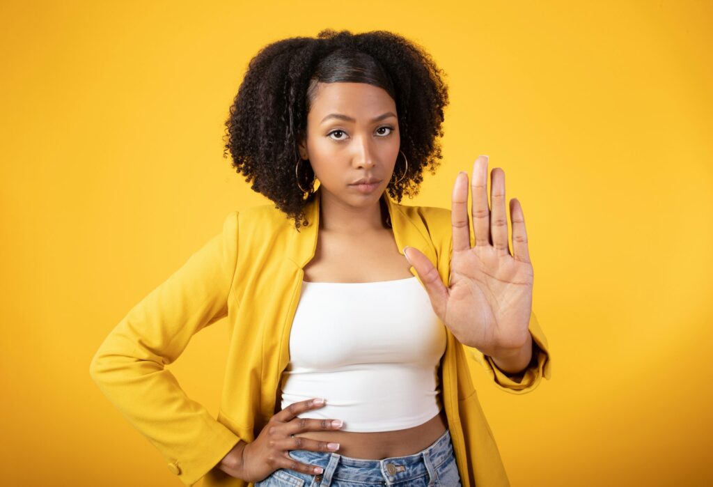 Young african american woman gesturing STOP and looking at camera with serious face expression